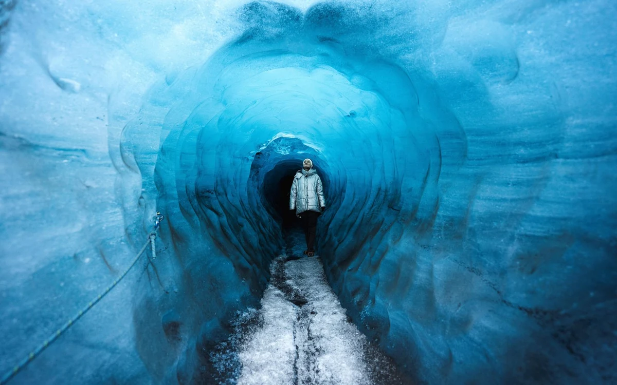 A guided group standing inside the ash-striped ice of the Katla cave