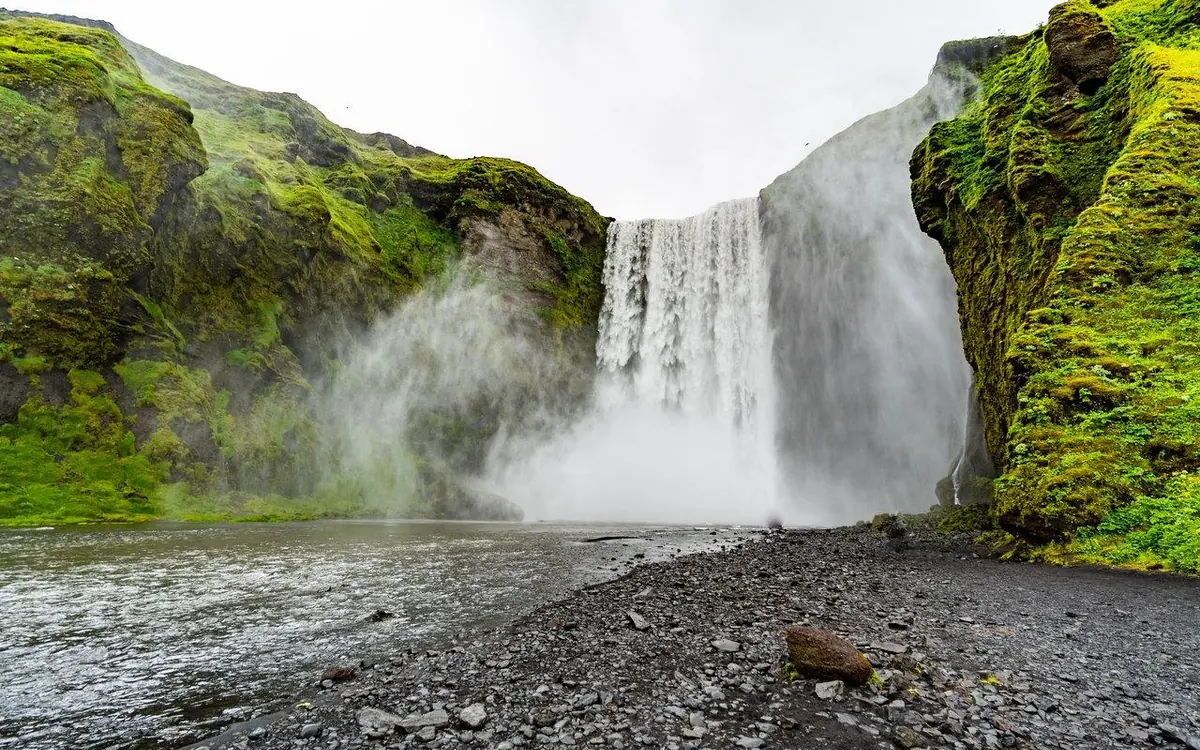 A wide waterfall falling into a green valley on the south coast